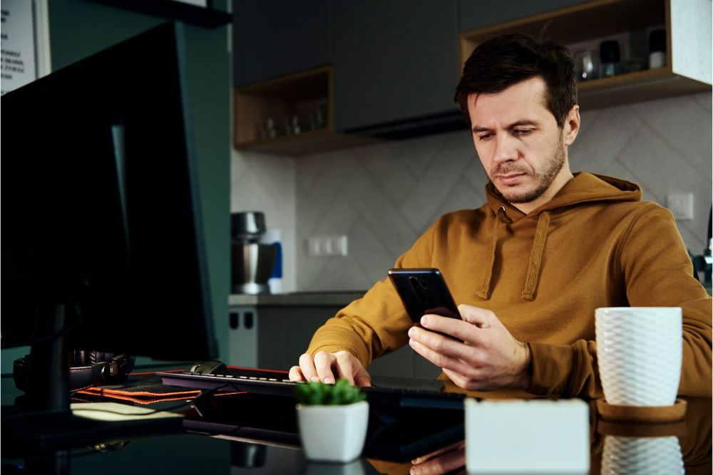 over-employed employee on a video call while looking at his phone