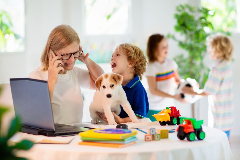 Remote interview questions: how do deal with the challenges of working from home? A woman on the phone with a puppy and children.