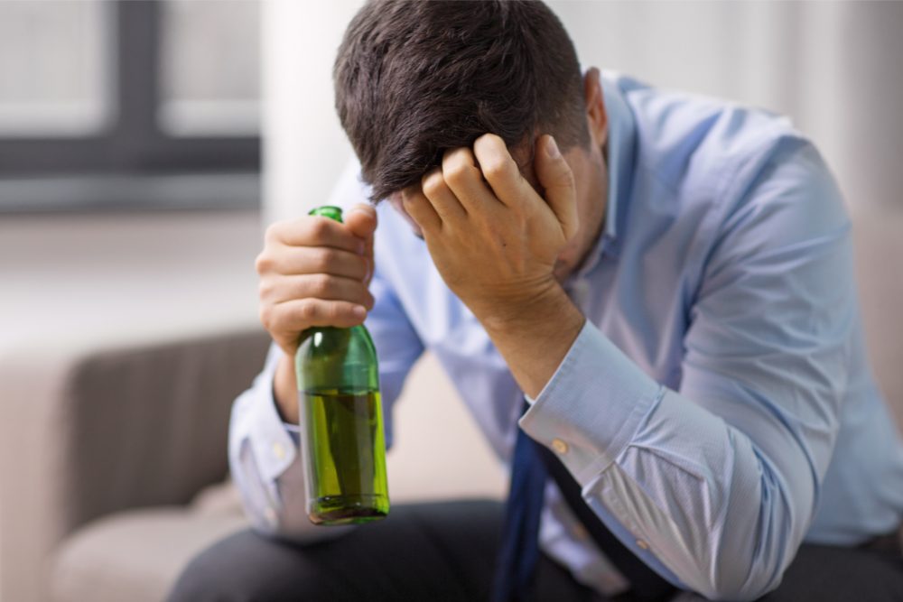 Anguished man. Employees drinking alcohol while working from home is dangerous for many reasons.