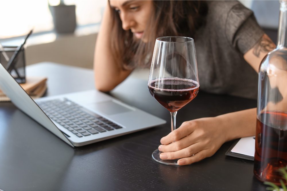 Female employee drinking while working from home.